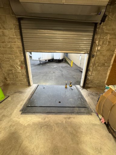 View of a loading dock with a raised door and concrete floor leading to an enclosed space.